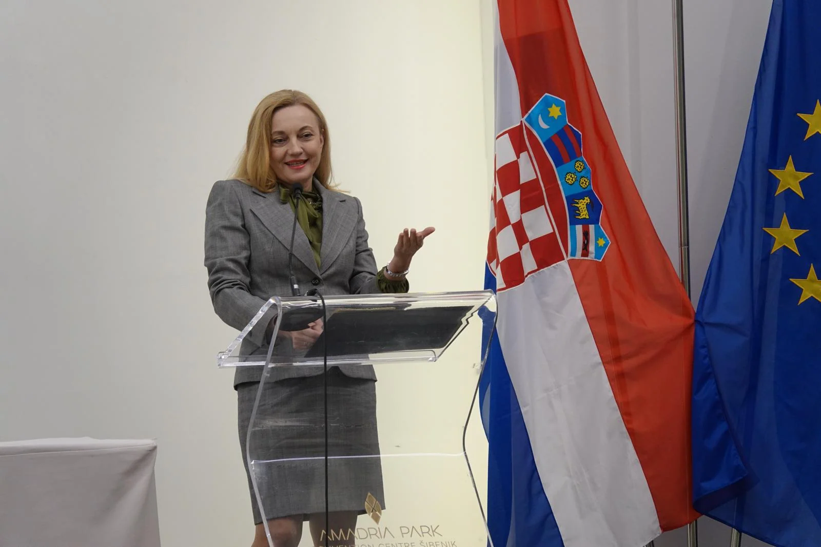 Govornica na konferenciji u Šibeniku, uz hrvatsku i europsku zastavu.