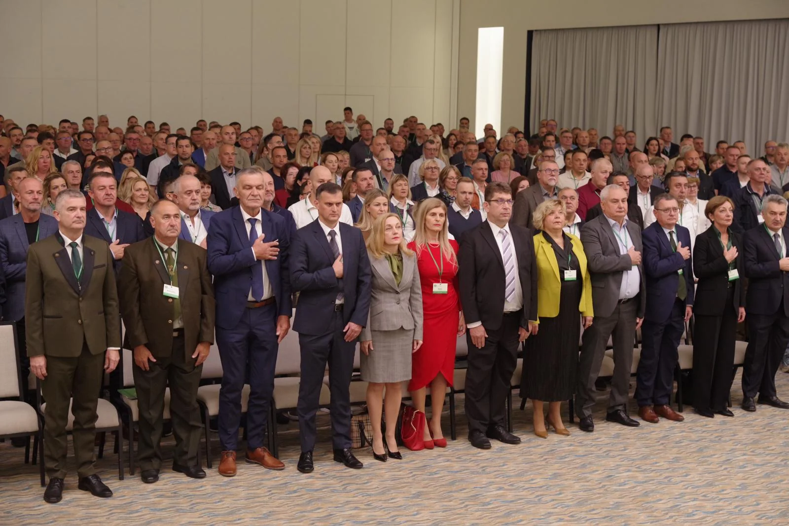 Sudionici stoje u konferencijskoj dvorani.